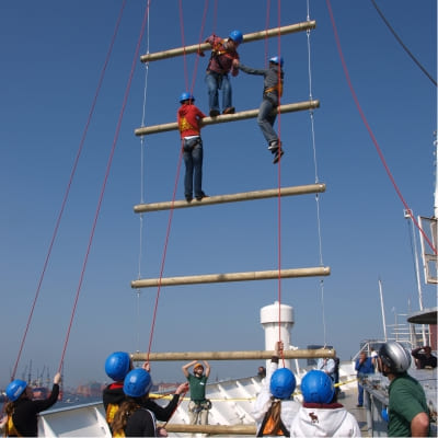 Drei Jugendliche helfen sich gegenseitig beim erklimmen der Kletteranlage auf dem Cap San Diego Schiff einige andere Teilnehmer schauen ihnen dabei zu