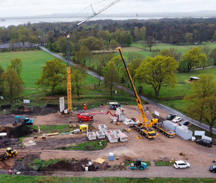 �berblick �ber die SkyLoop-Baustelle in Mardorf mit Kran, Aufzugsturm-Bauteilen und dem Steinhuder Meer im Hintergrund